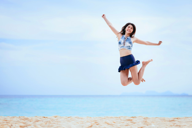 mujer-feliz-saltando-playa_34840-18