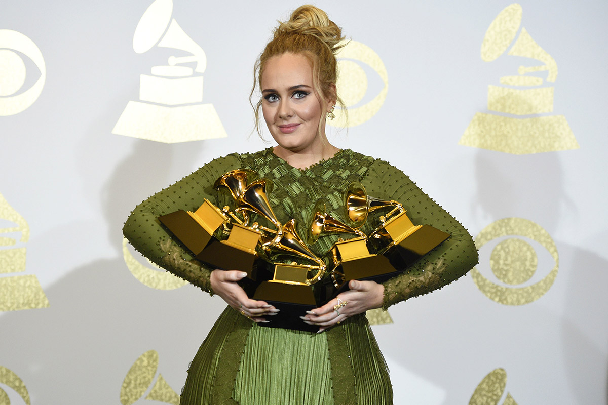 Singer Adele poses in the press room with the awards for album of the year for "25", song of the year for "Hello", record of the year for "Hello", best pop solo performance for "Hello", and best pop vocal album for "25" in the press room at the 59th annual Grammy Awards on Sunday, Feb. 12, 2017, in Los Angeles.