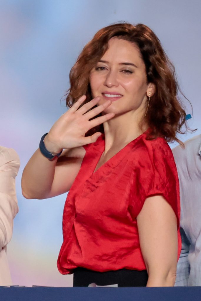 Isabel Díaz Ayuso vestida de rojo y saludando.