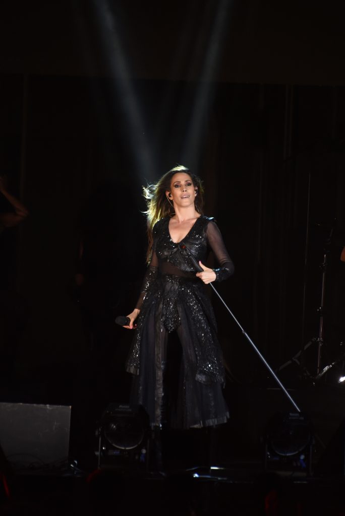 Malú vestida con transparencias en color negro mientras sujeta un micrófono.