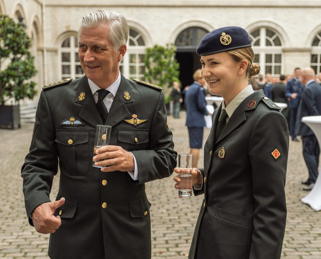 elisabeth de belgica y su padre, el rey felipe, vestidos de militares y celebrando con un vaso de agua