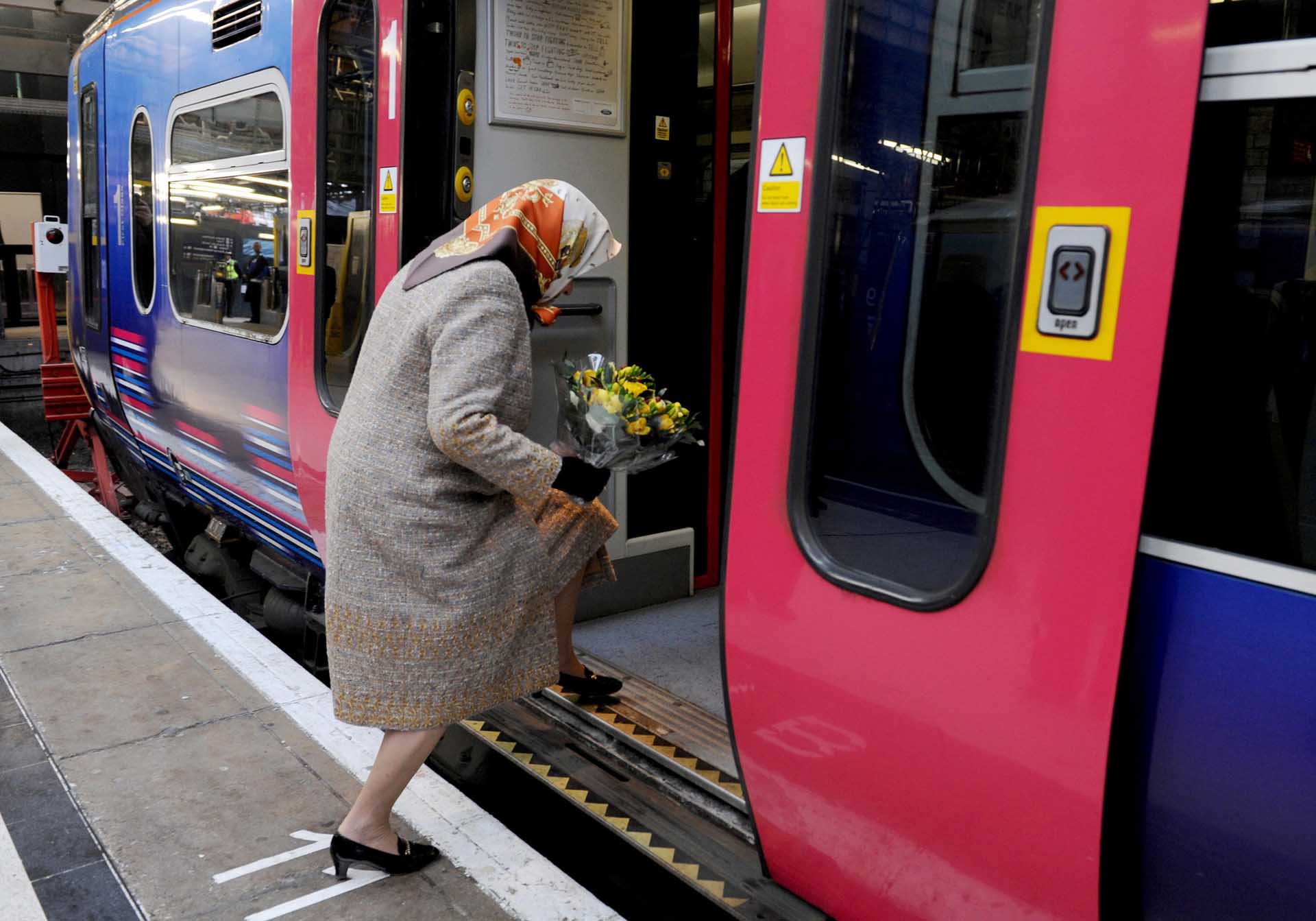 La reina subiéndose a un tren con un ramo de flores