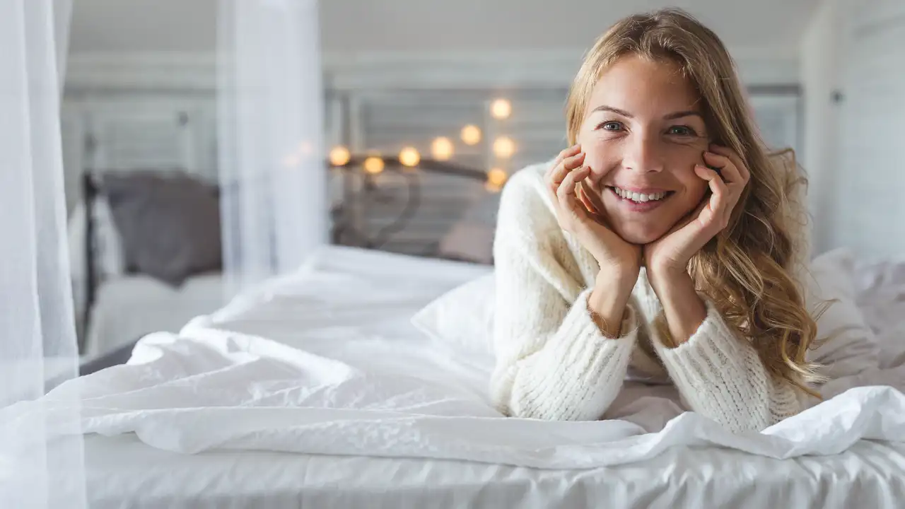 Mujer rubia sonríe en la cama