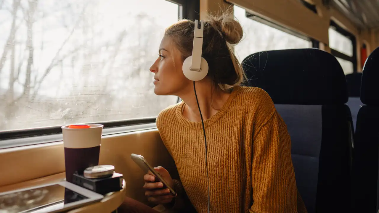 Mujer en el tren con el móvil y auriculares