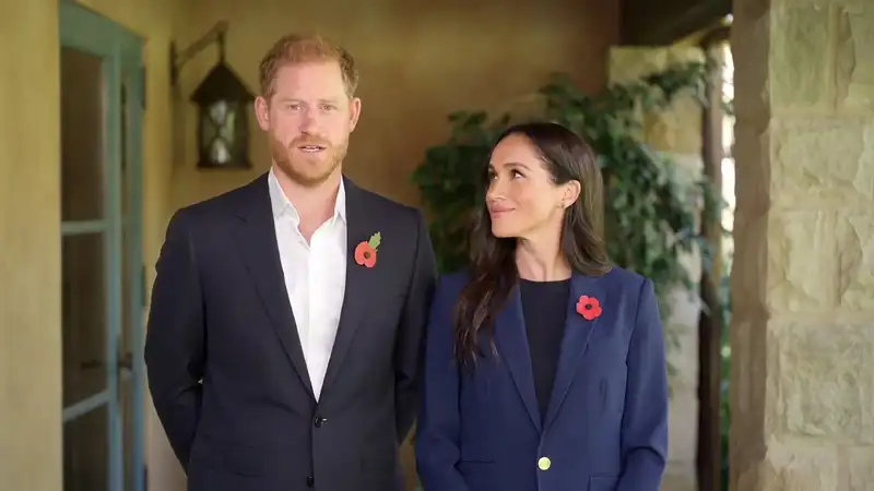 Meghan, ligeramente adelantada, dedica una mirada a su marido, el Príncipe Harry, sin acompañar el gesto con el cuerpo. 