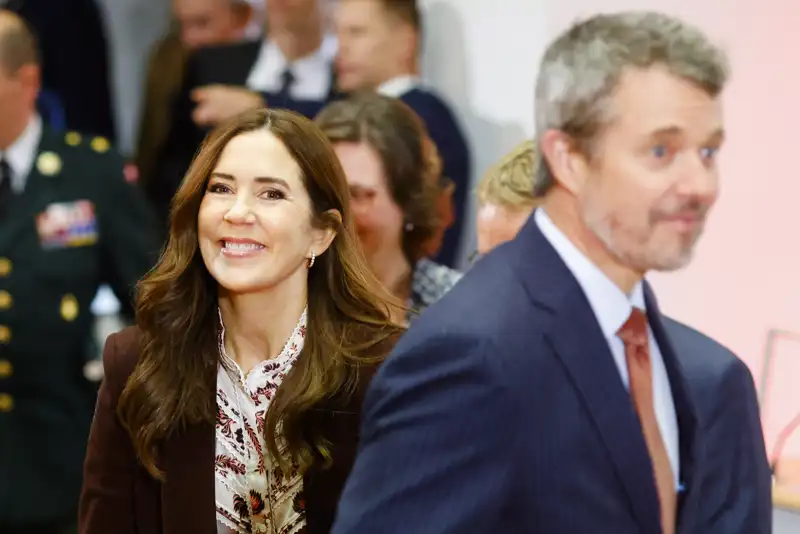 La Reina Mary sonríe a cámara un paso por detrás de un Federico X desenfocado.