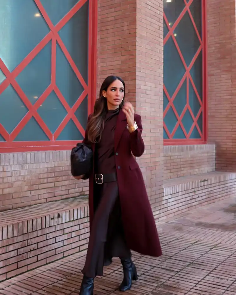 El abrigo burgundy que mejor combina con el vestido satinado y un bolso de altos vuelos