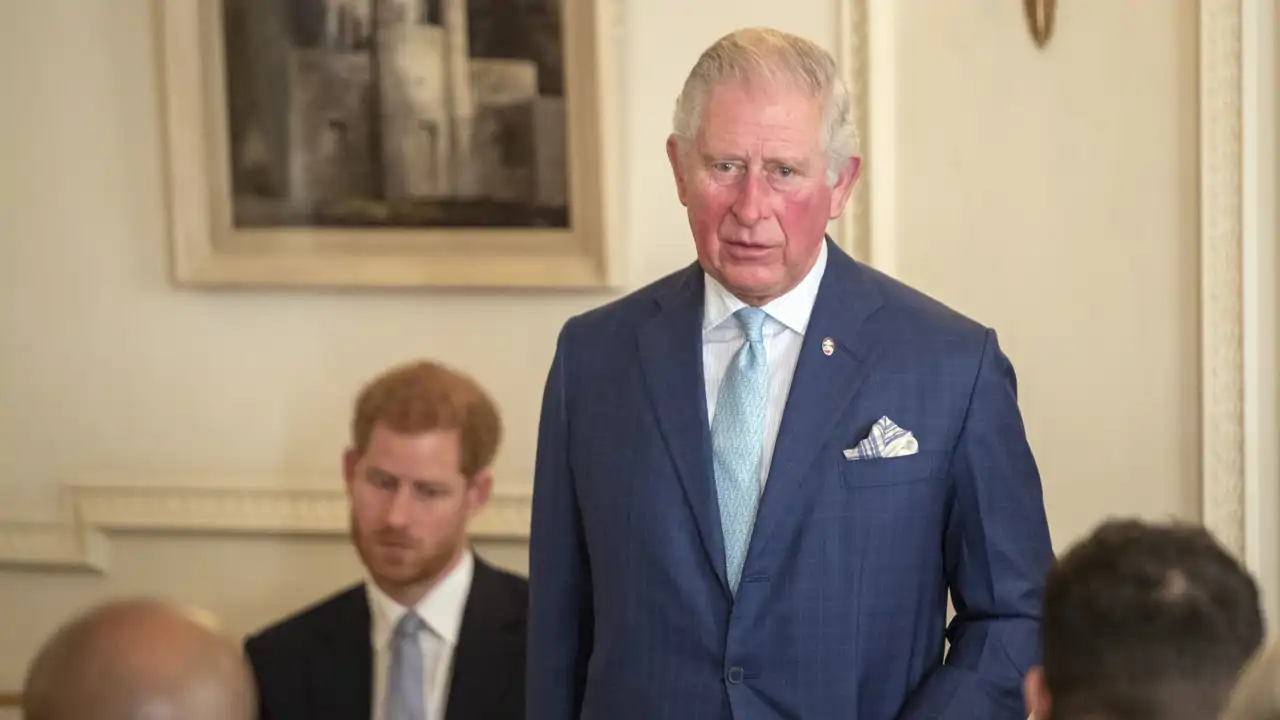El rey Carlos III y su hijo menor, el príncipe Harry, al fondo