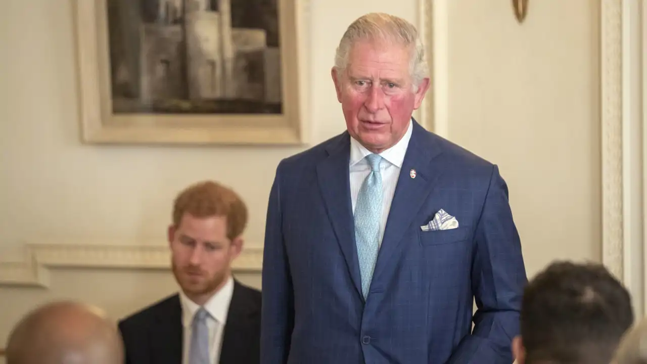 El rey Carlos III y su hijo menor, el príncipe Harry, al fondo