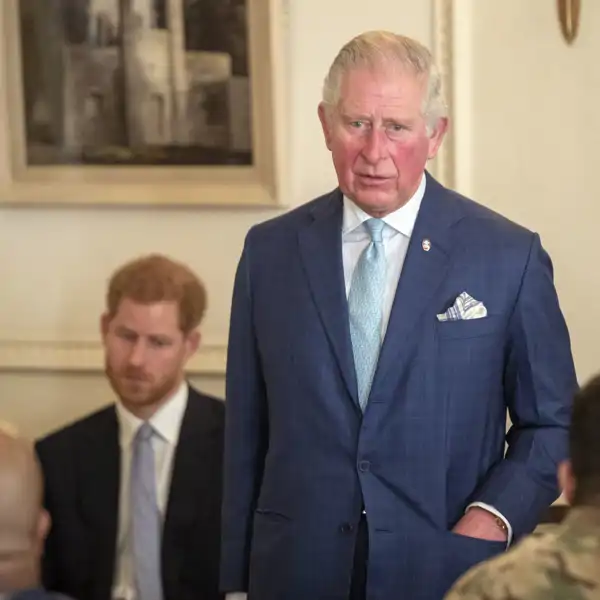 El rey Carlos III y su hijo menor, el príncipe Harry, al fondo