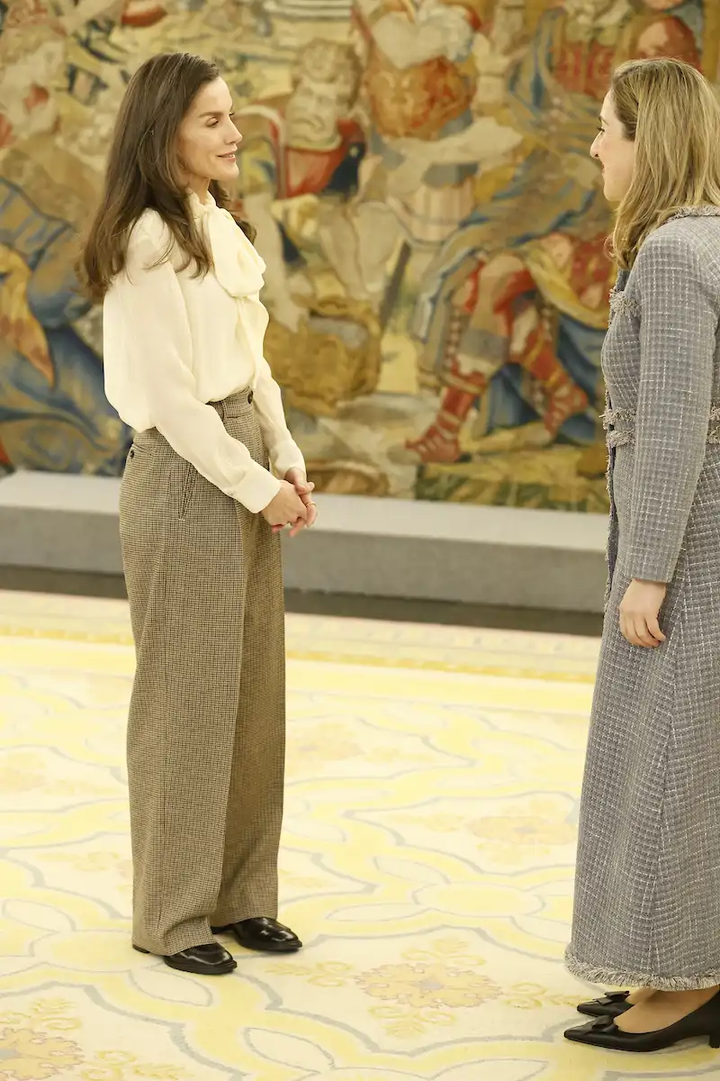 La Reina Letizia se ha decantado por una blusa pussy bow de color blanca firmada por Carolina Herrera de líneas fluidas. 