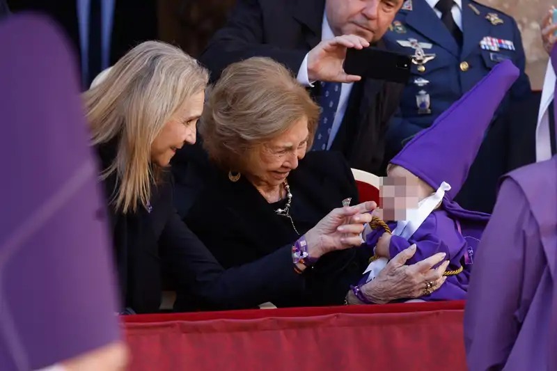 La Reina Sofía y la Infanta Elena interactuando con un niño nazareno