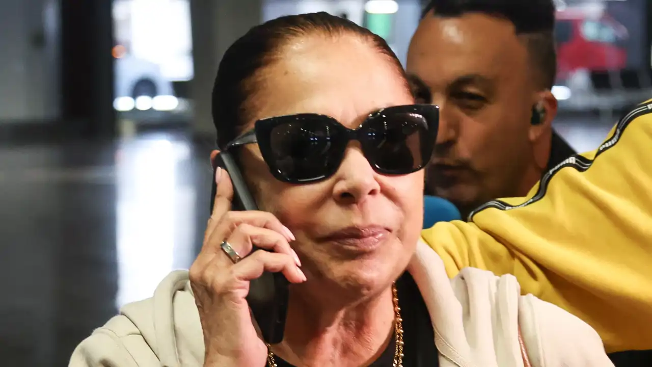 Isabel Pantoja, en su llegada al aeropuerto de Madrid con su teléfono móvil en la mano